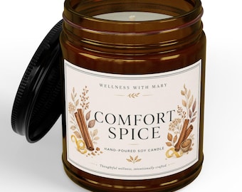 May include: A brown glass jar candle with a black lid, featuring a white label with the text Comfort Spice, Wellness with Mary, and Hand-Poured Soy Candle. The label includes watercolor illustrations of cinnamon sticks and dried botanical elements.