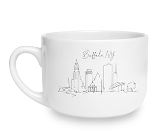May include: A white ceramic mug featuring a black continuous line drawing of the Buffalo, New York skyline. The design includes various city buildings and a buffalo silhouette, with the text Buffalo, NY written in a cursive script above the art.