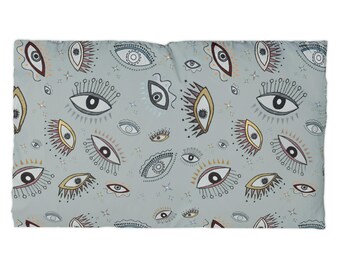 May include: A rectangular fabric textile featuring a repeating pattern of stylized eyes in various shapes and sizes. The eyes are rendered in black, white, gold, and maroon outlines against a solid light gray background, interspersed with small star icons.