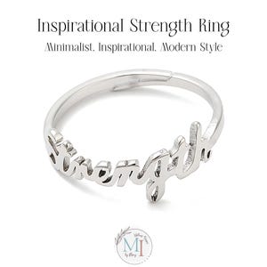 May include: Silver ring with the word "strength" written in a cursive font.