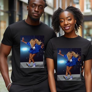 May include: Two black short-sleeved crew neck t-shirts featuring a graphic print of a person with blonde curly hair wearing a blue jacket, blue skirt, and blue sneakers, captured in a dynamic pose on a stage with blue lighting effects.