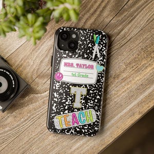 May include: Black and white notebook-style phone case with colorful stickers. The stickers say "Mrs. Taylor 1st Grade" and "Teach".