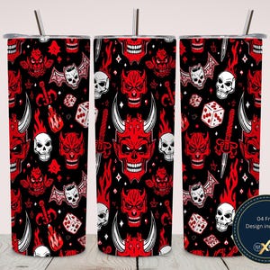 May include: Three cylindrical tumblers with straws featuring a repeating pattern of red horned devil faces, white skulls, dice, and daggers on a black background. A circular badge in the bottom right corner displays the text 04 Free Design included.
