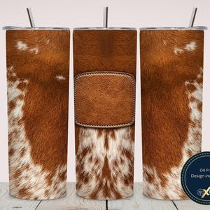 May include: A set of three stainless steel tumblers with lids and straws. The tumblers feature a brown and white cowhide pattern. One tumbler has a brown leather patch design. The tumblers are cylindrical and are on a wooden surface.