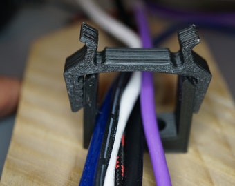 May include: A black plastic cable management clip holds a bundle of wires, including blue, white, black, and purple wires.