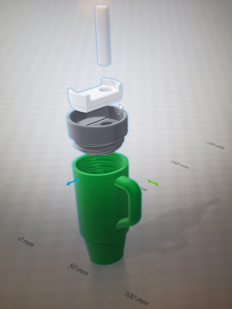 May include: A green travel mug with a handle and a white lid. The mug is disassembled to show the different parts. The mug is 150 mm tall and 50 mm wide.