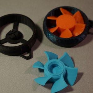 May include: Three 3D printed fan blades. One is black, one is blue, and one is orange with a black housing. The orange fan is attached to a black chain.