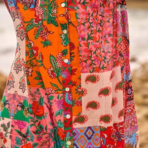 Puede incluir: Una camisa abotonada con un dise&ntilde;o de patchwork vibrante que presenta varios patrones florales, de cachemira y geom&eacute;tricos en tonos naranja, rosa, rojo, verde y azul. La prenda tiene una tapeta central vertical con botones blancos.