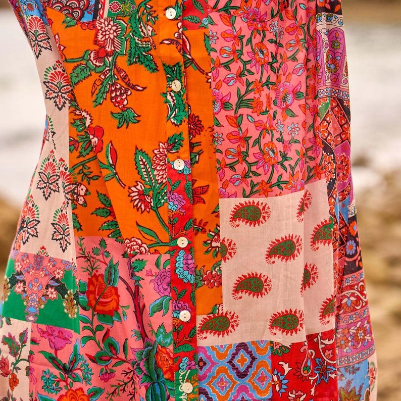 Puede incluir: Una camisa abotonada con un dise&ntilde;o de patchwork vibrante que presenta varios patrones florales, de cachemira y geom&eacute;tricos en tonos naranja, rosa, rojo, verde y azul. La prenda tiene una tapeta central vertical con botones blancos.