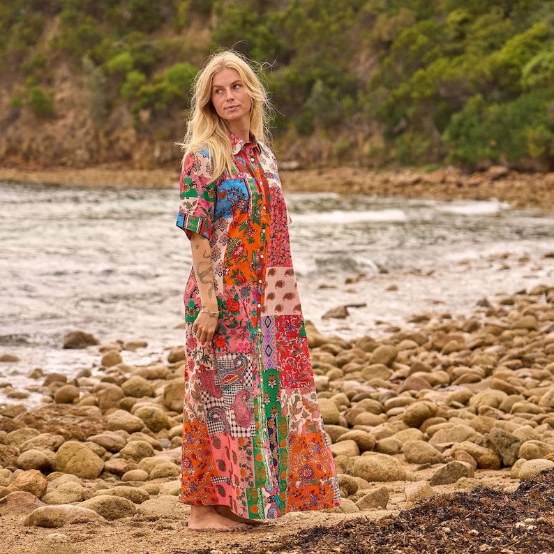 Puede incluir: Un vestido largo de manga larga con un dise&ntilde;o de patchwork vibrante que presenta varios estampados florales y de cachemira en tonos naranja, rosa, verde y azul. El vestido tiene un cierre frontal de botones, un cuello cl&aacute;sico y una silueta fluida.