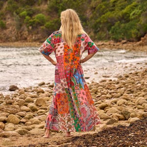 Puede incluir: Un vestido largo hasta los pies con un dise&ntilde;o de patchwork vibrante que presenta varios estampados florales y de cachemira en tonos naranja, rosa, azul, verde y blanco. La prenda tiene mangas cortas y una silueta holgada y fluida hasta los tobillos.