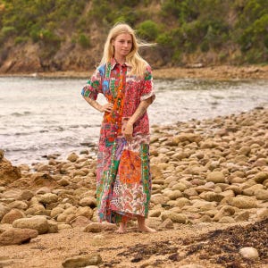 Puede incluir: Un vestido largo de manga larga con botones frontales que presenta un dise&ntilde;o de patchwork vibrante con varios patrones florales, de cachemira y geom&eacute;tricos en tonos naranja, rosa, verde, azul y blanco, con cuello y silueta fluida.