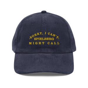 Peut inclure: Une casquette de baseball en velours côtelé bleu marine avec le texte "Désolé, je ne peux pas. Spielberg pourrait appeler." brodé en jaune.