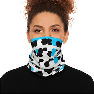 Puede incluir: Un cubrecuello blanco, negro y azul claro con un patrón geométrico repetitivo. El cubrecuello se lleva alrededor del cuello y cubre la parte inferior de la cara. El patrón consiste en hexágonos negros y blancos con detalles en azul claro.