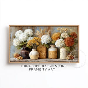 May include: A framed artwork featuring a still life of flowers in various vases. The arrangement includes white, yellow, and orange blooms, with dried grasses. The vases are in shades of brown and cream, set against a rustic wooden background.