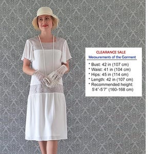 May include: A white knee-length dress with short flutter sleeves and a light gray lace panel across the chest and hips. The garment features a bust of 42 inches, waist of 41 inches, hips of 45 inches, and a length of 42 inches for heights 5'4"-5'7".