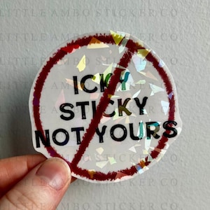 May include: A round sticker with a red circle and a diagonal line through it. The sticker says "icky sticky not yours" in black text.