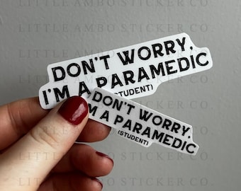 May include: Two white stickers with black text. The top sticker reads "Don't worry, I'm a paramedic (student)". The bottom sticker reads "Don't worry, I'm a paramedic (student)".