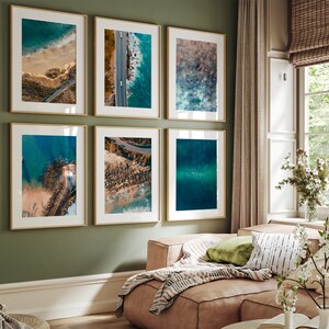 Collection of six framed prints showcasing Australia's diverse coastline, arranged above a plush sofa. Each piece, from the golden sands to the rugged cliffs and blue waters, reflects an aspect of the coast, complementing the earthy living space.