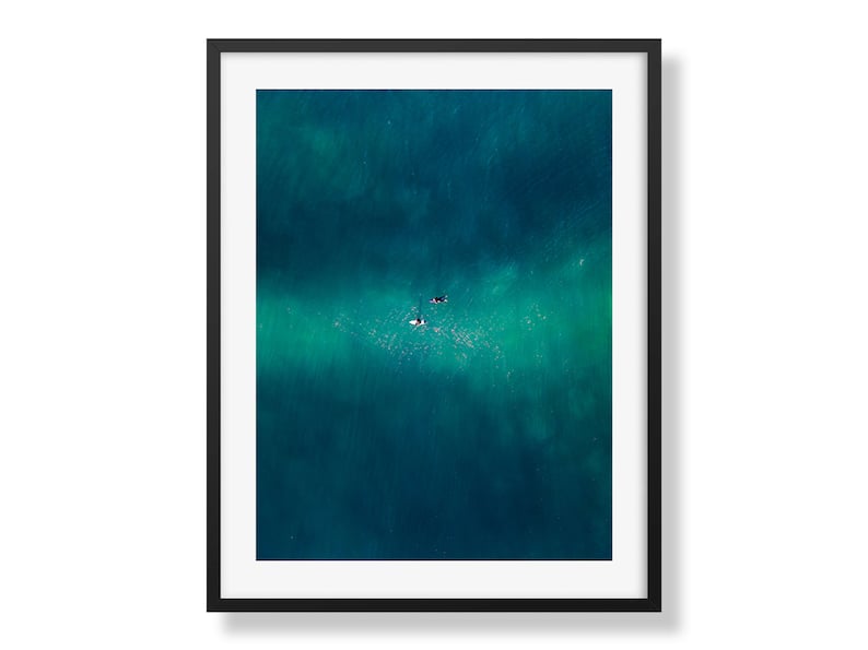 Crisp black-framed print of early dawn at Cronulla, with two surfers floating on gentle waves, encapsulating the calm of the ocean