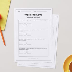 May include: White printed worksheets with word problems for addition and subtraction. An orange pen with a pom-pom top rests on a yellow notepad. A yellow saucer with a cup of coffee is in the bottom right corner.