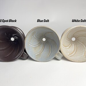 May include: Three ceramic pour-over coffee makers in Oil Spot Black, Blue Salt, and White Salt. Each has a central hole and a handle. The names of the colors are written above each coffee maker.