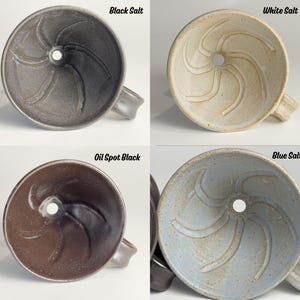May include: Four ceramic funnels in different colors: black, white, oil spot black, and blue. Each funnel has a handle and a central hole. The text "Black Salt", "White Salt", "Oil Spot Black", and "Blue Salt" is visible above each funnel.