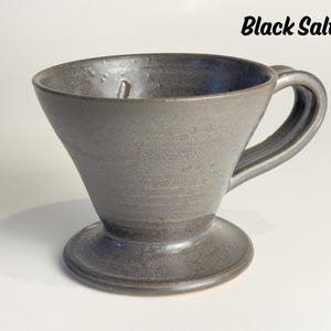 May include: A handmade, dark gray ceramic pour-over coffee maker with a handle and a wide base. The words "Black Salt" are written in black script at the top right.
