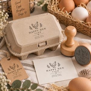 Puede incluir: Una huevera de pulpa beige, un sello de madera, una tarjeta rectangular y una etiqueta de papel marrón, todos con un logotipo negro de una gallina con el texto Happy Hen Farm, Fresh Eggs, Better Days y un pequeño símbolo de corazón.