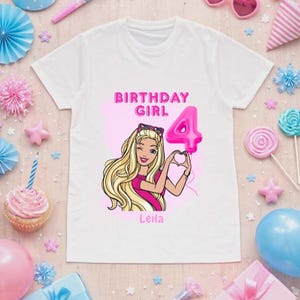 May include: A white t-shirt featuring a graphic print of a blonde character with long hair, wearing pink clothing and sunglasses, making a heart shape with hands. The text reads BIRTHDAY GIRL, the number 4 in pink, and the name Leila in pink.