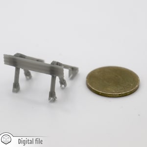Peut inclure: Un petit modèle gris imprimé en 3D d'une structure de support métallique. Le modèle est à peu près de la taille d'une pièce de 1 euro.