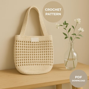 May include: Cream-coloured crochet tote bag with a rectangular open weave design. The bag has a solid base and handles, with a small rectangular tag. The words "CROCHET PATTERN" and "PDF DOWNLOAD" are in the background.