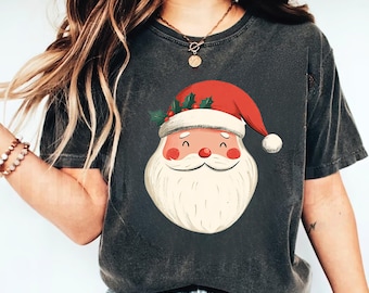 Op de afbeelding: Een donkergrijs T-shirt met een cartoon afbeelding van het gezicht van Sinterklaas. Sinterklaas draagt een rode muts met witte rand en een witte baard.