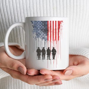 May include: White ceramic mug featuring a stylized American flag design with a distressed effect. The flag transitions into a dripping pattern, with the silhouettes of four soldiers standing at the bottom. The mug has a white handle.
