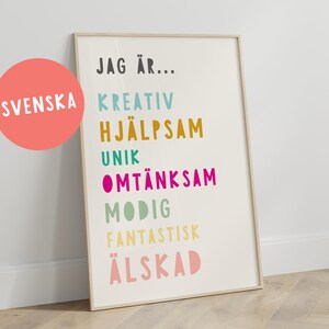 以下が含まれることがあります： 「JAG ÄR...」という黒いテキストと、「KREATIV」、「HJÄLPSAM」、「UNIK」、「OMTÄNKSAM」、「MODIG」、「FANTASTISK」、「ÄLSKAD」という様々な色の単語が書かれた額縁付きポスター。ポスターは明るい木製の床の上に置かれている。