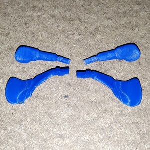 Puede incluir: Cuatro piezas de plástico azul, posiblemente para un juego o un juguete, con una forma curva y un pequeño agujero en el extremo.