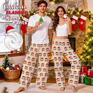 May include: Custom flannel pajama pants with a repeating pattern of a dog wearing a Santa hat. The pants are beige with a soft, fuzzy texture. The image also shows a close-up of the fabric and the text "Custom Flannel Pajama Pants".