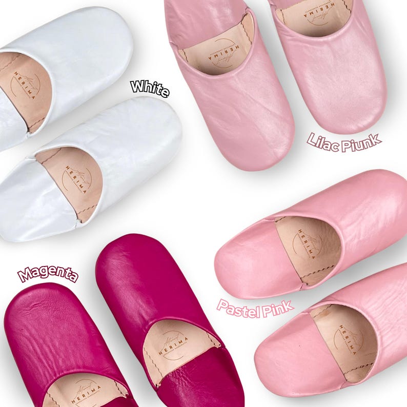 Puede incluir: Cinco pares de zapatillas de cuero en diferentes colores: blanco, rosa lila, magenta, rosa pastel. Las zapatillas son todas del mismo estilo, con punta puntiaguda y parte trasera cerrada.