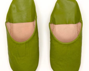 May include: A pair of green leather slippers. The slippers have a pointed toe and a closed back. The slippers are made of a soft, supple leather and have a comfortable fit.