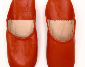May include: A pair of orange leather slippers. The slippers are made of soft, supple leather and have a comfortable fit.