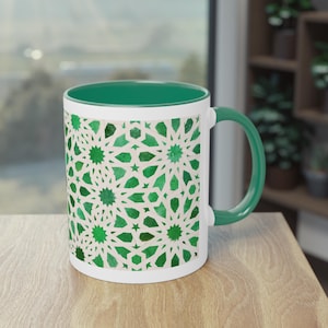 Peut inclure: Une tasse en céramique blanche avec une bordure et une poignée vertes. La tasse présente un motif géométrique vert et blanc.