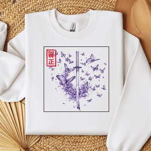May include: White sweatshirt with a purple and black graphic design of a katana sword with butterflies and the Japanese word "Seigi" in red.