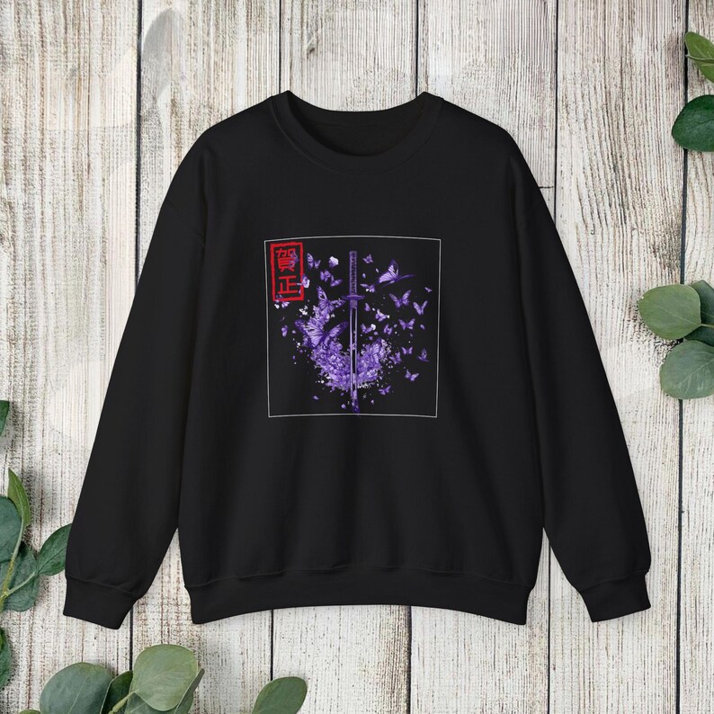 May include: Black sweatshirt with a graphic print of a purple sword surrounded by purple butterflies. The graphic is in a square frame with a red square in the top left corner that contains Japanese characters.