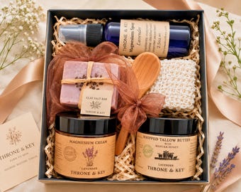 May include: A gift box containing a blue bottle of Throne & Key Magnesium Spray, a Clay Salt Bar, a wooden spoon, a white textured sponge, a jar of Magnesium Cream, and a jar of Whipped Tallow Butter with Manuka Honey, all nestled in wood shavings.