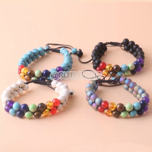 Könnte beinhalten: Vier Armbänder mit bunten Perlen und schwarzer Schnur. Die Armbänder bestehen aus verschiedenen Materialien, darunter türkisfarbene, weiße, schwarze und schillernde Perlen.
