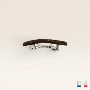 Peut inclure: Une barrette à cheveux incurvée présentant un motif écaille de tortue brun foncé avec une finition polie. L'accessoire comprend un mécanisme de fermeture à ressort en métal argenté sur le dessous pour fixer les cheveux, avec le texte HAND MADE IN FRANCE.