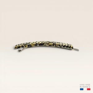 Peut inclure: Une barrette à cheveux incurvée présentant un motif à damier dans des tons noir, blanc et crème. L'accessoire possède un mécanisme de fermeture métallique sur le dessous et inclut le texte "HAND MADE IN FRANCE" avec un petit drapeau bleu, blanc, rouge.