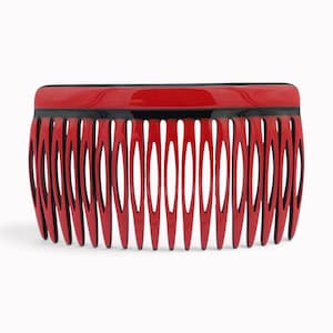 Pode incluir: Um pente de cabelo com uma barra superior vermelha lisa e brilhante e uma série de dentes vermelhos longos e pontiagudos. A base dos dentes é acentuada com uma fina borda preta, criando um design de alto contraste com formato retangular.