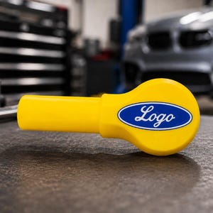 May include: A bright yellow tool handle featuring a rounded end with a blue oval emblem in the centre. The emblem contains the white script text Logo. The handle has a cylindrical shaft and a wider, flattened head section with a smooth finish.