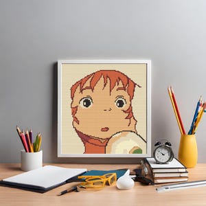 May include: A framed cross-stitch artwork featuring a cartoon girl with red hair and a white dress. The girl has a surprised expression on her face.